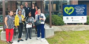 wellness employees stand at a sign